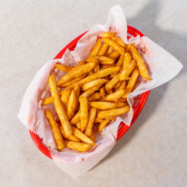 Golden brown french fries in a red plastic basket lined with white paper.