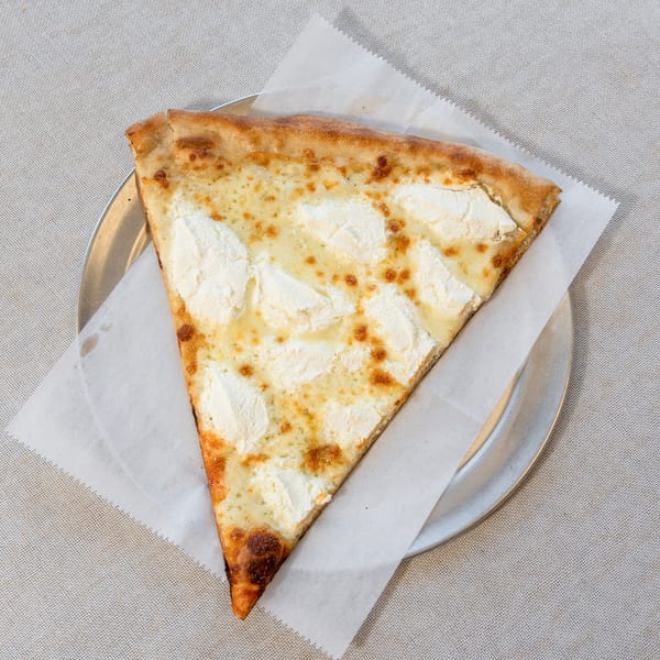 A single slice of white pizza with ricotta cheese dollops and golden crust on a metal plate.