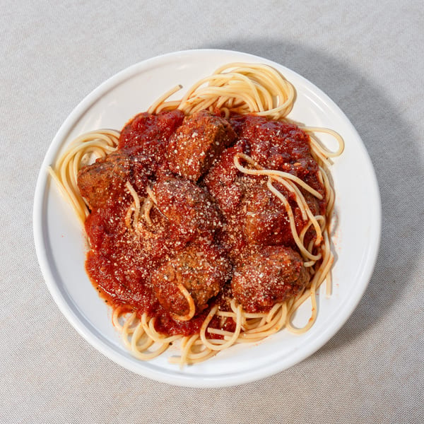 Spaghetti with meatballs and tomato sauce, topped with grated Parmesan cheese on a white plate.